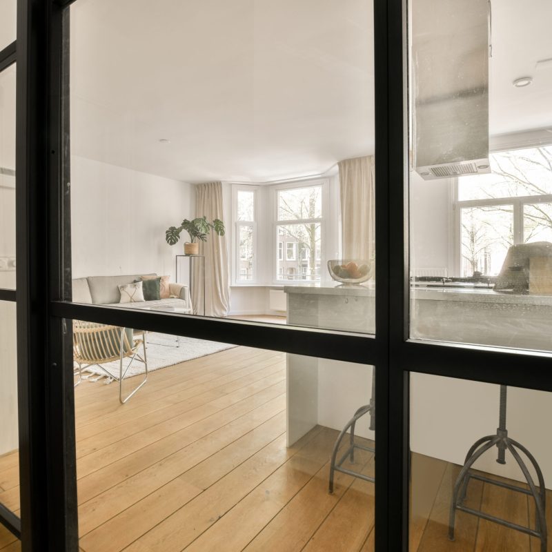 Table with chairs and flowers located near lounge area and kitchen in spacious room of contemporary apartment