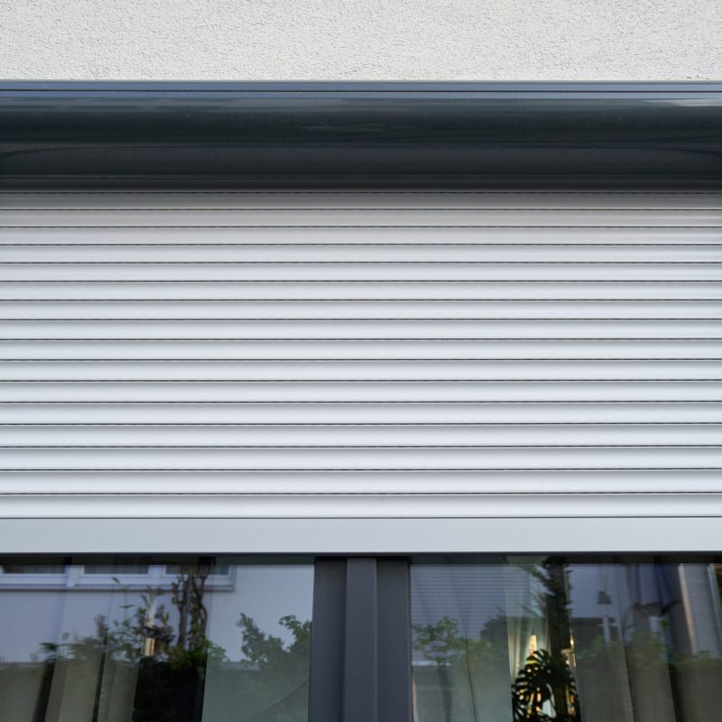 Roller shutter curtains mounted on a dark window