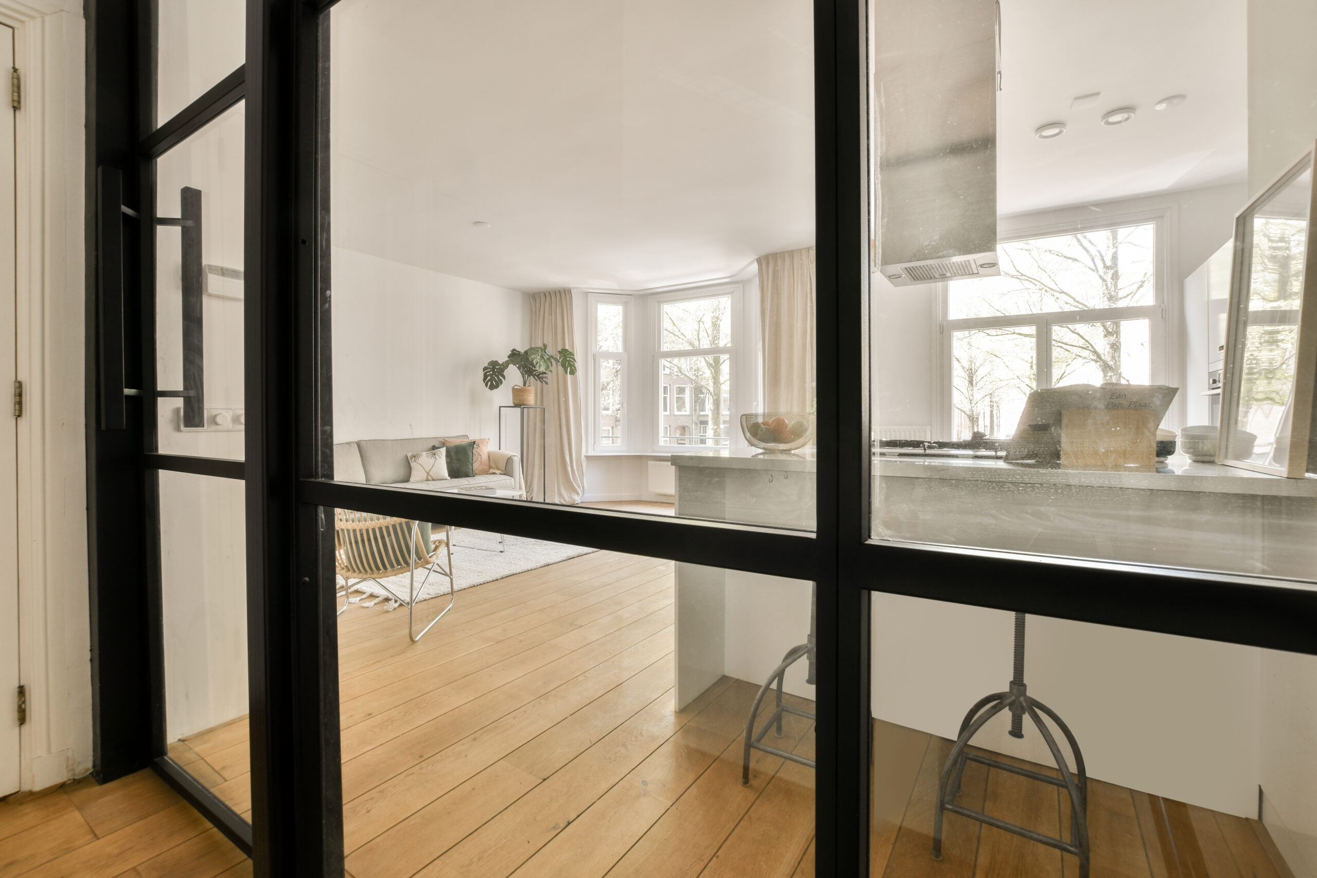 Table with chairs and flowers located near lounge area and kitchen in spacious room of contemporary apartment